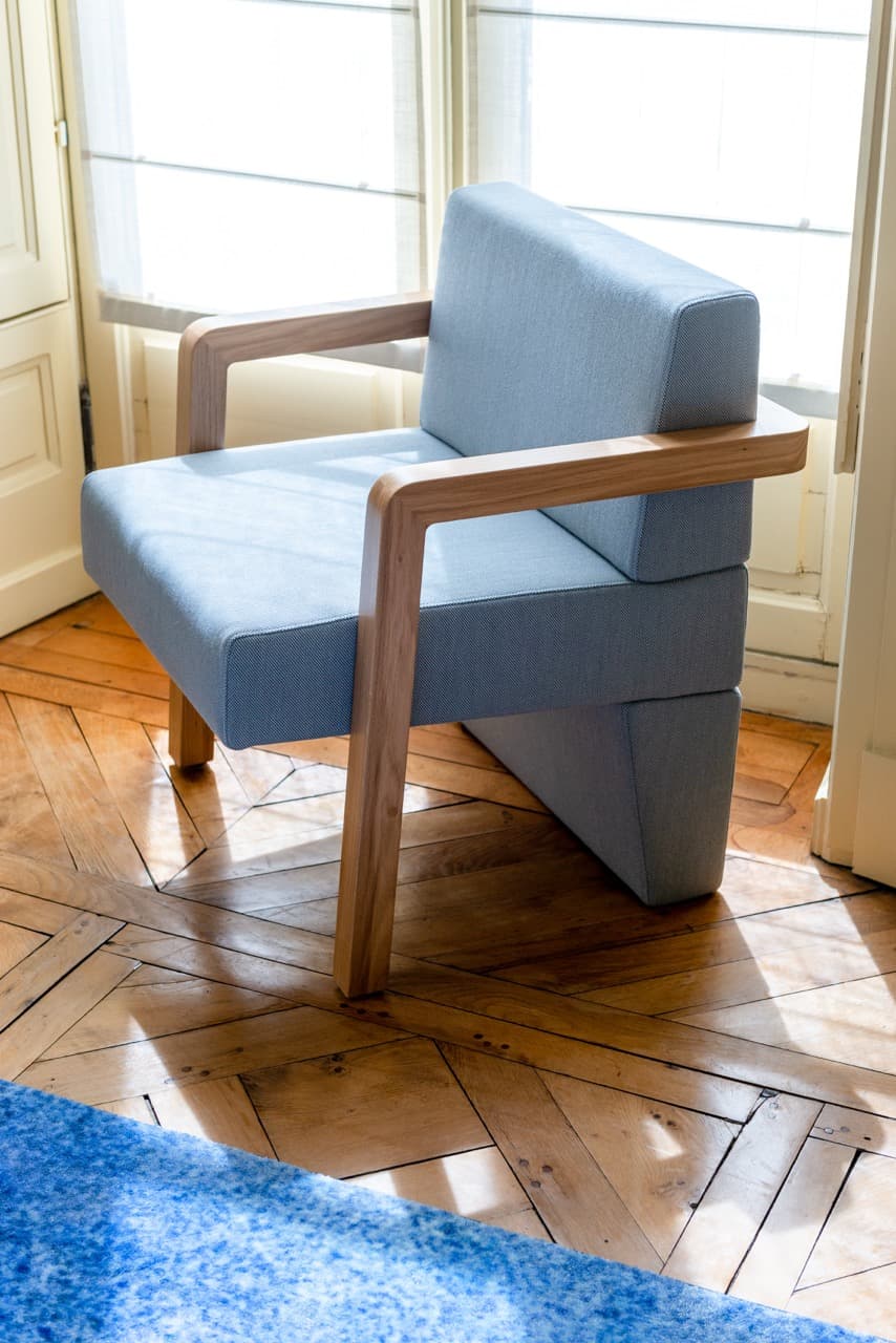 Fauteuil en bois tapissé de bleu sur parquet en point de Hongrie