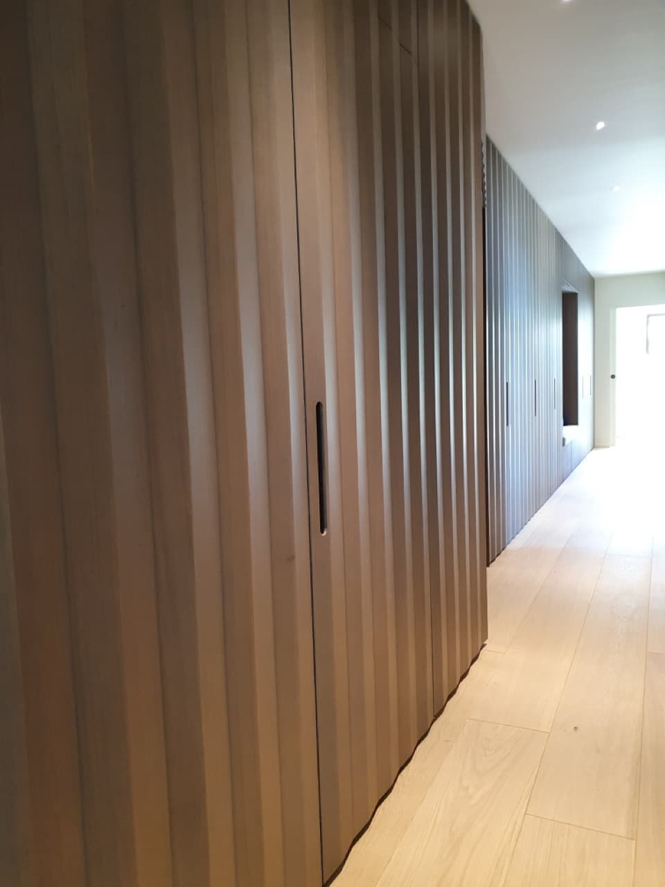 Façades de placards en chêne toute hauteur dans un couloir
