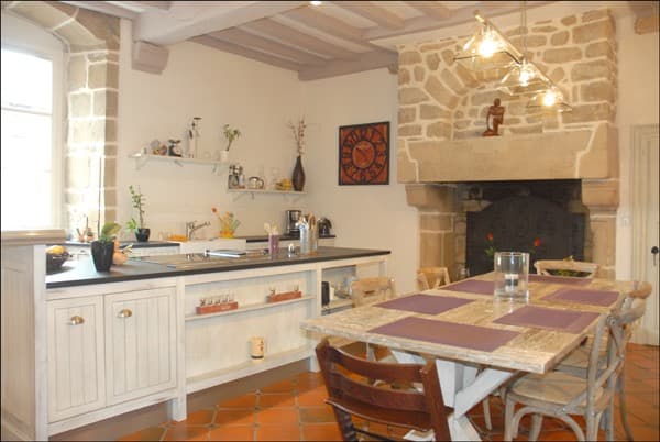 Cuisine rustique blanche avec cheminée en pierre et poutres apparentes