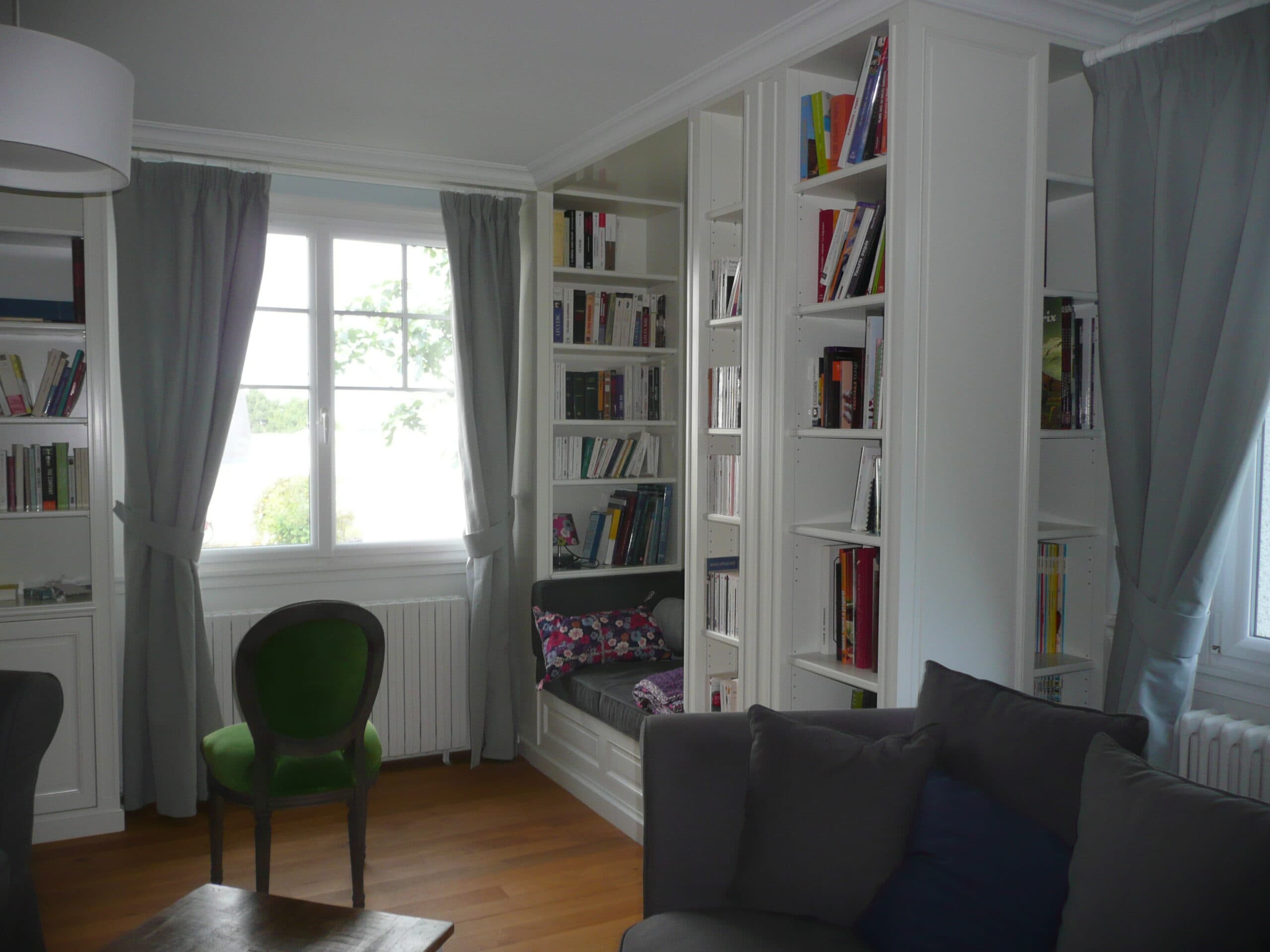 Bibliothèque blanche encadrant une fenêtre avec banquette