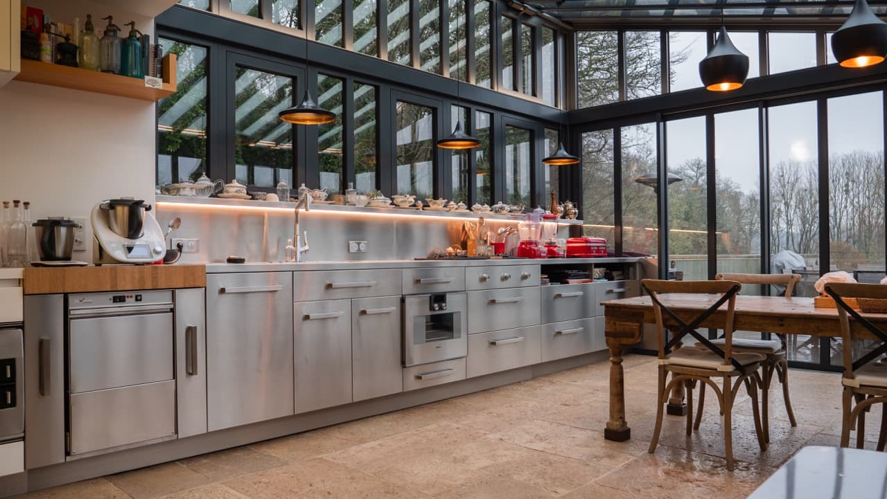 Cuisine inox sous verrière avec table et chaises bistrot