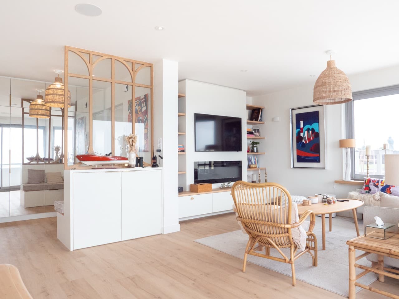 Séjour avec meuble TV blanc, verrière en bois et fauteuils en rotin
