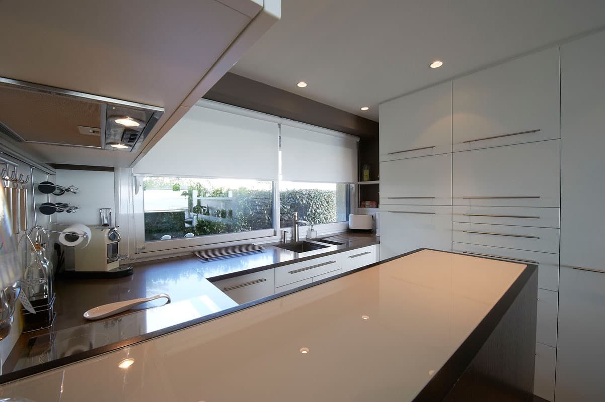 Plan de travail en quartz et rangements blancs avec vue sur jardin