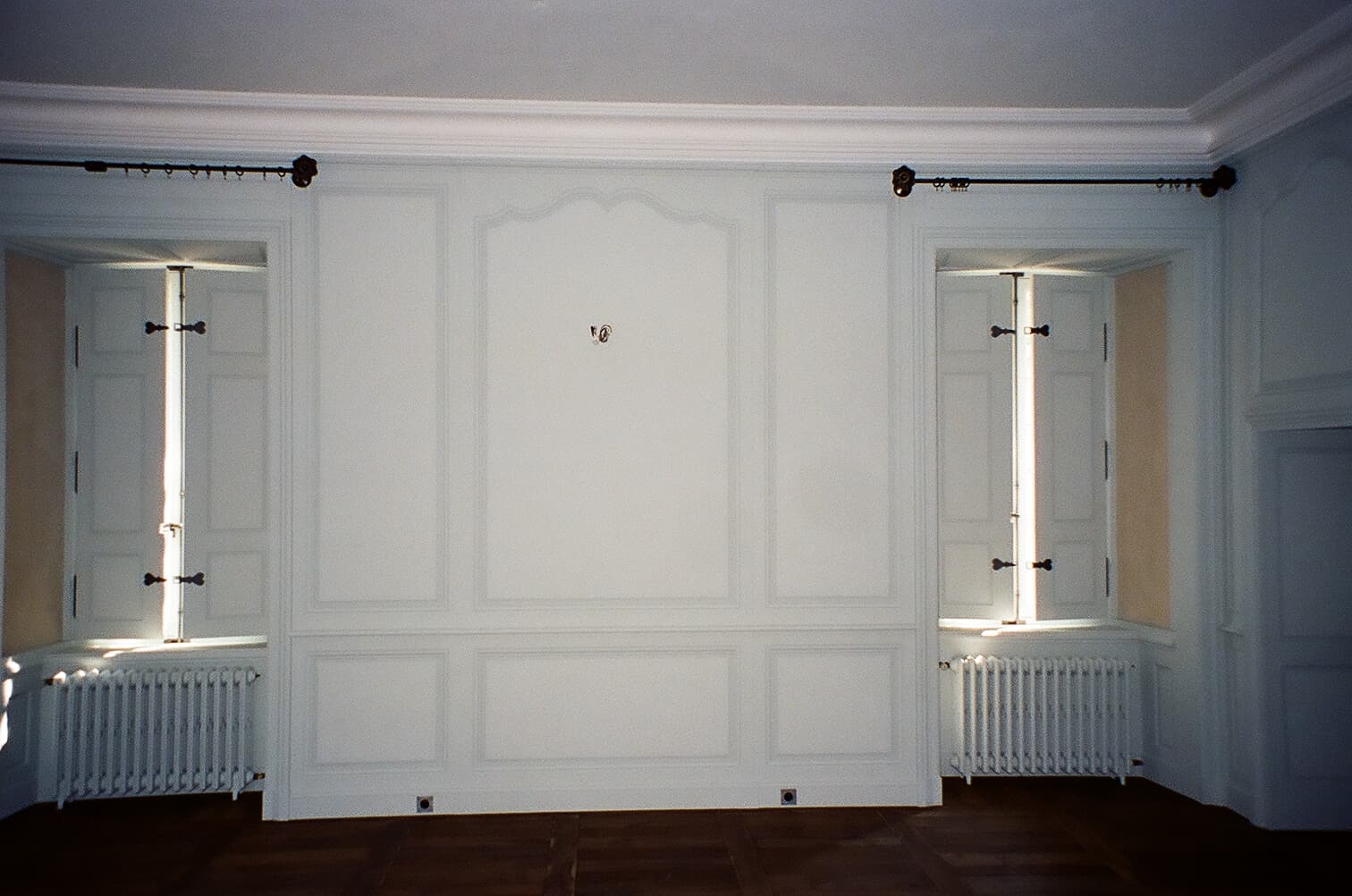 Boiseries blanches moulurées encadrant deux fenêtres