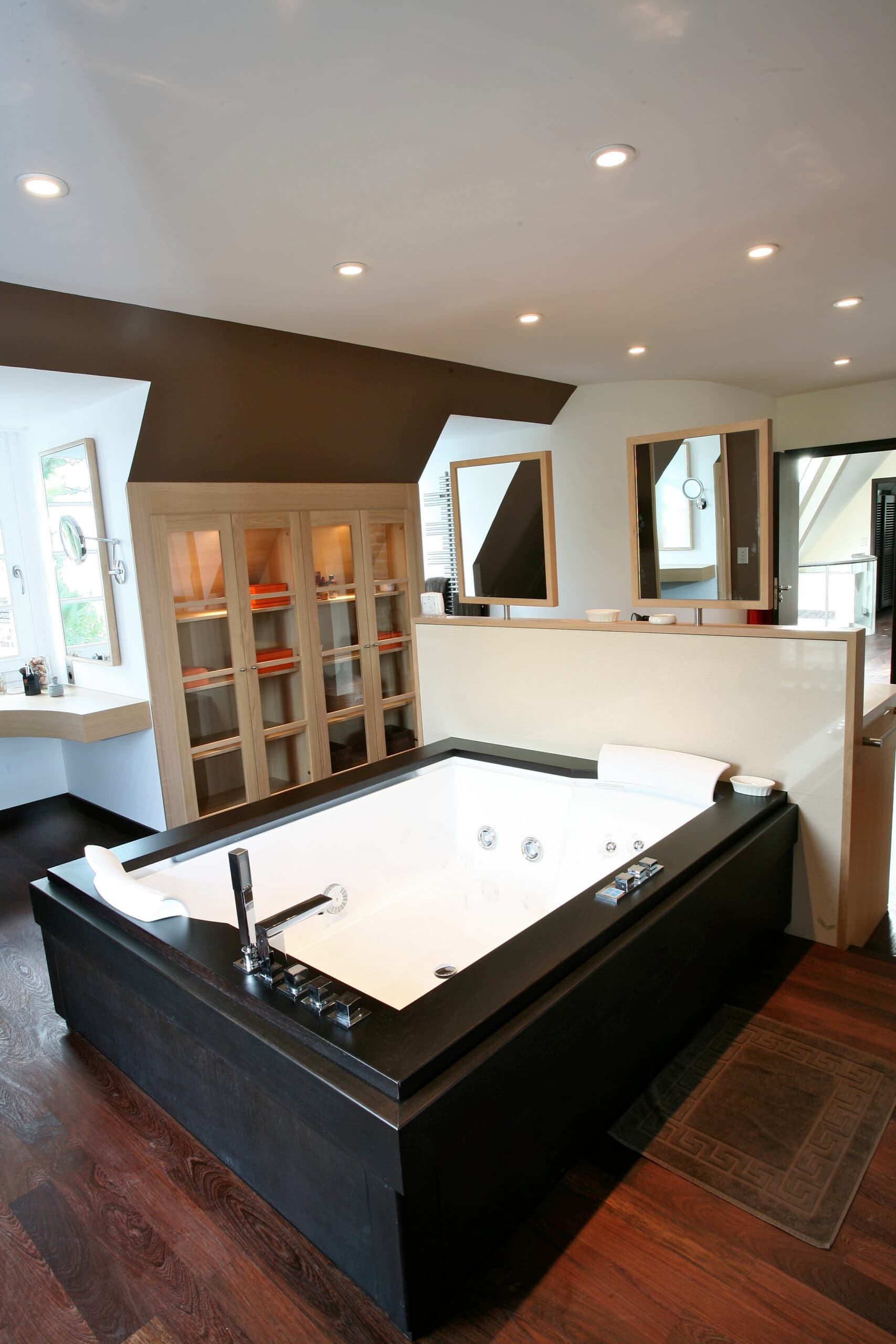 Salle de bain ouverte avec baignoire et parquet foncé