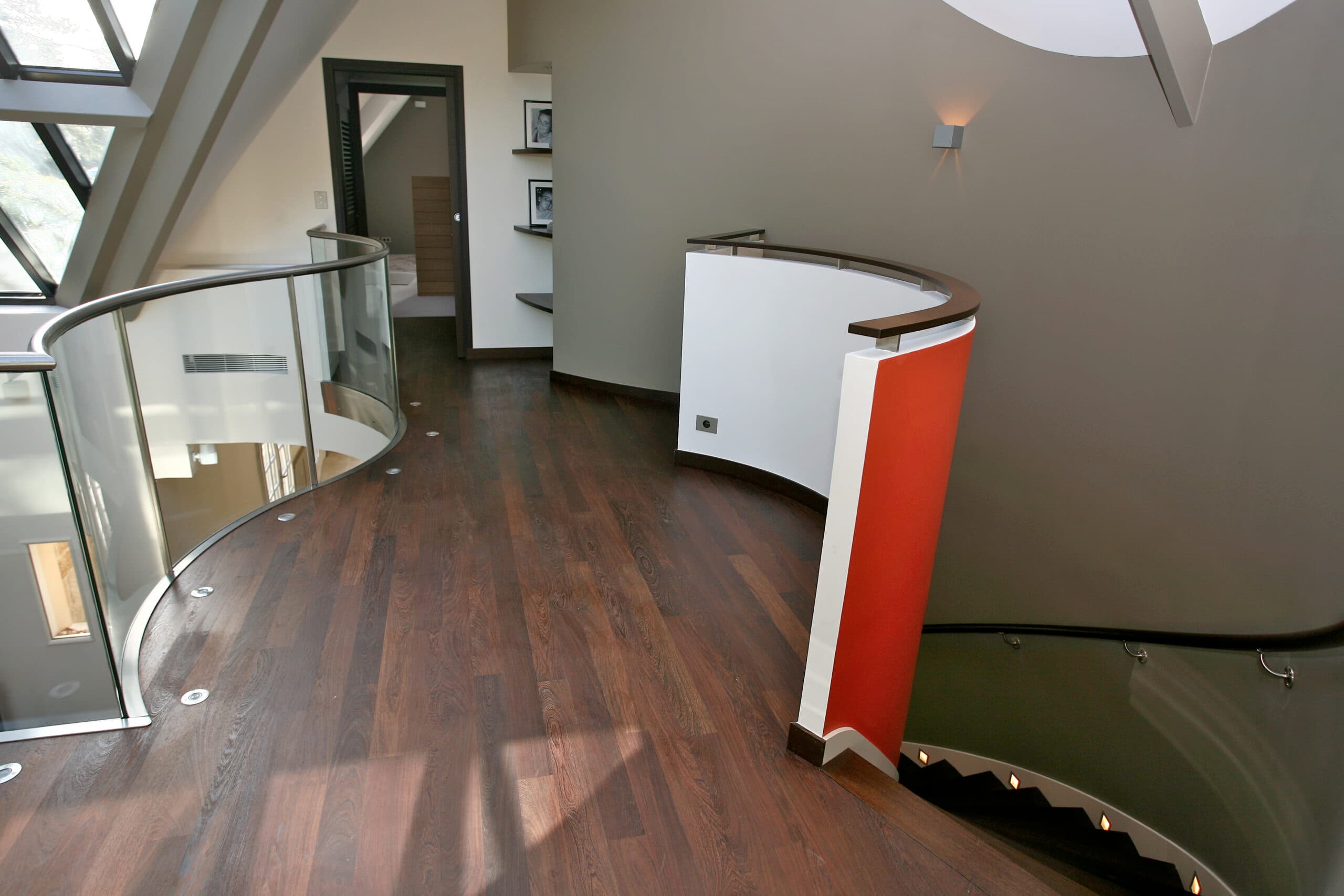 Parquet foncé autour d'un escalier avec rampe en verre