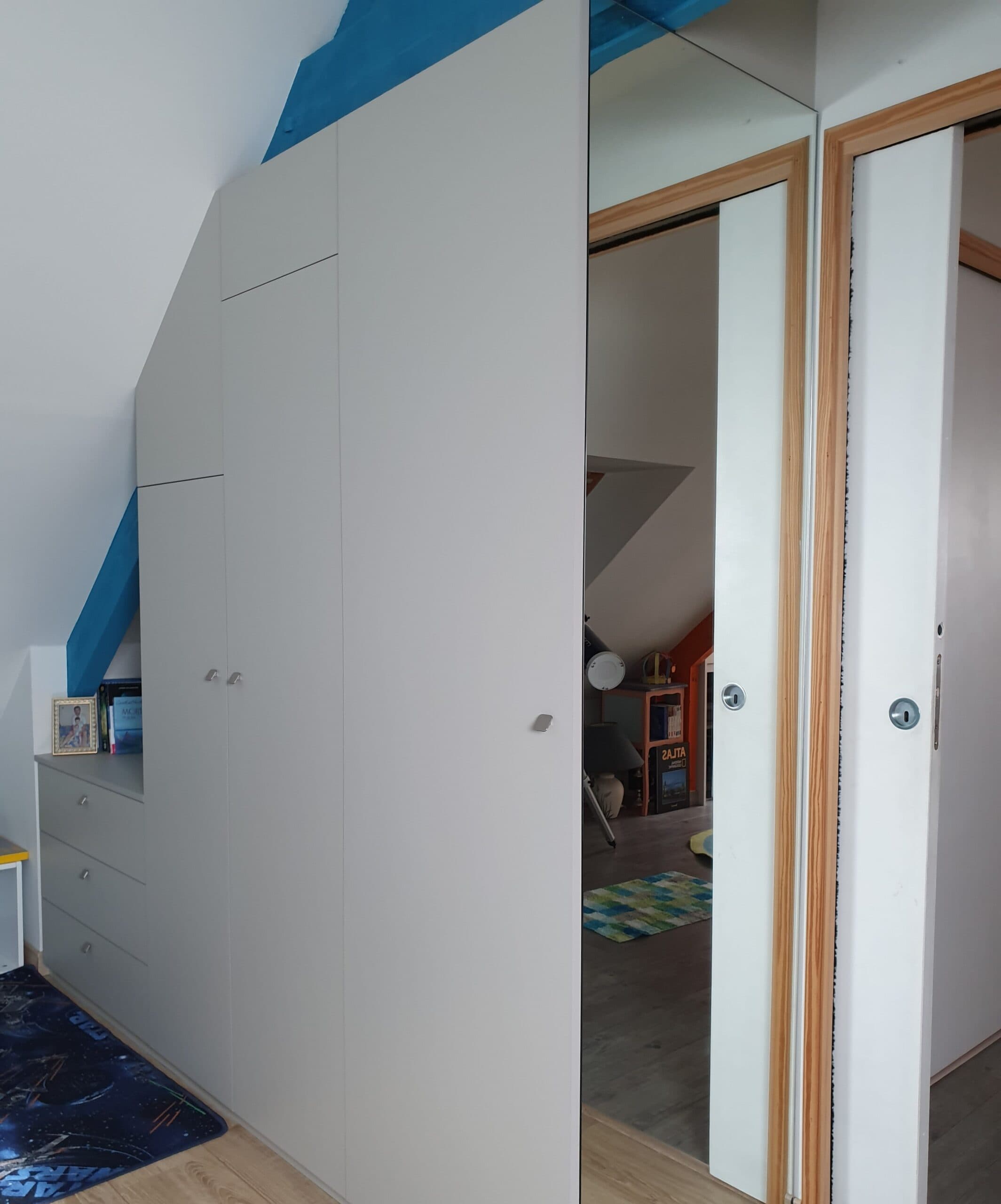Placard sous comble avec portes blanches et poutre bleue
