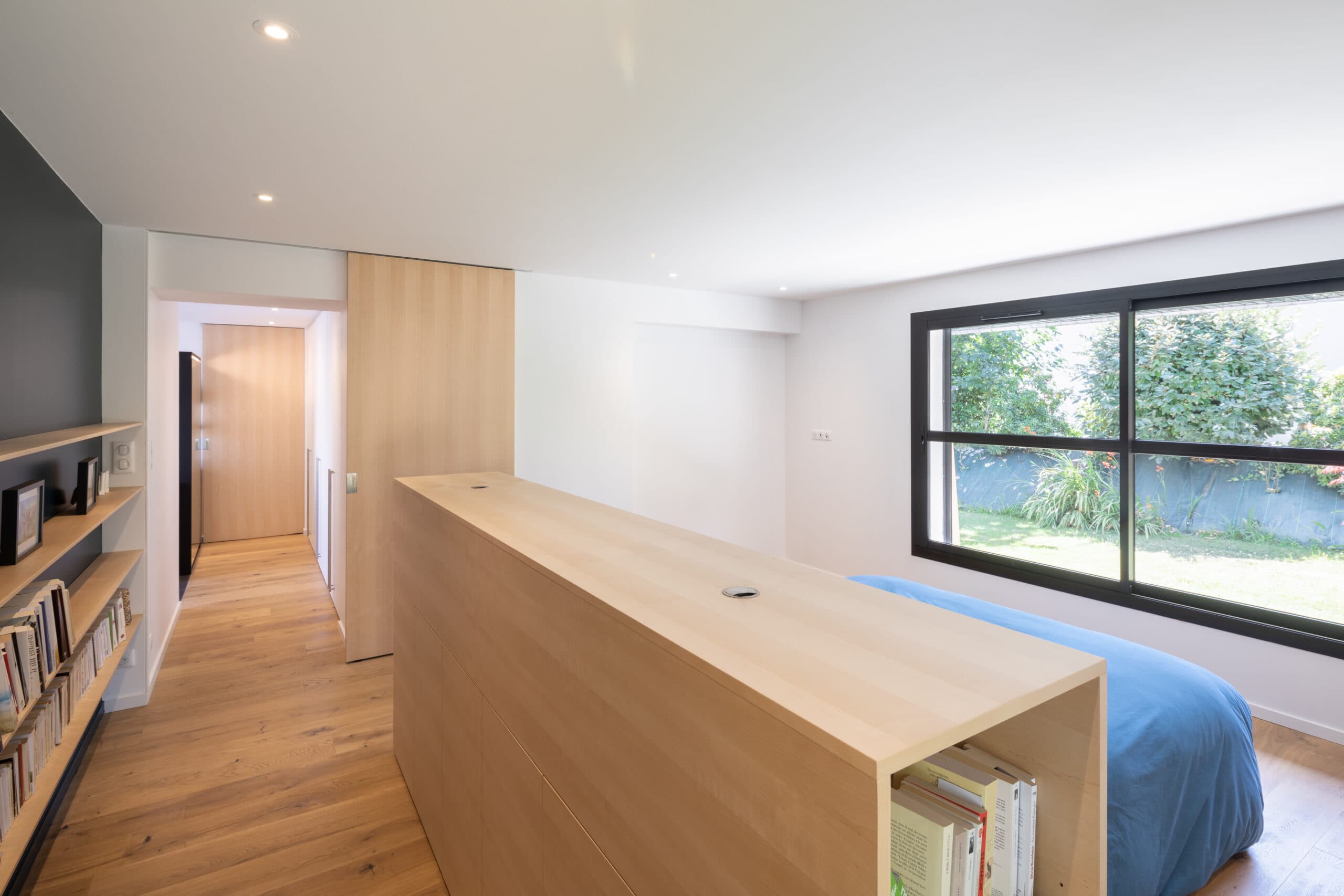 Chambre avec tête de lit en chêne servant de séparation