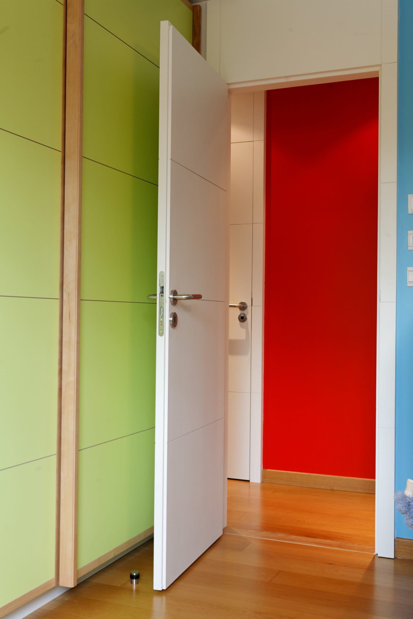 Portes de placard vertes et porte rouge dans une chambre d'enfant