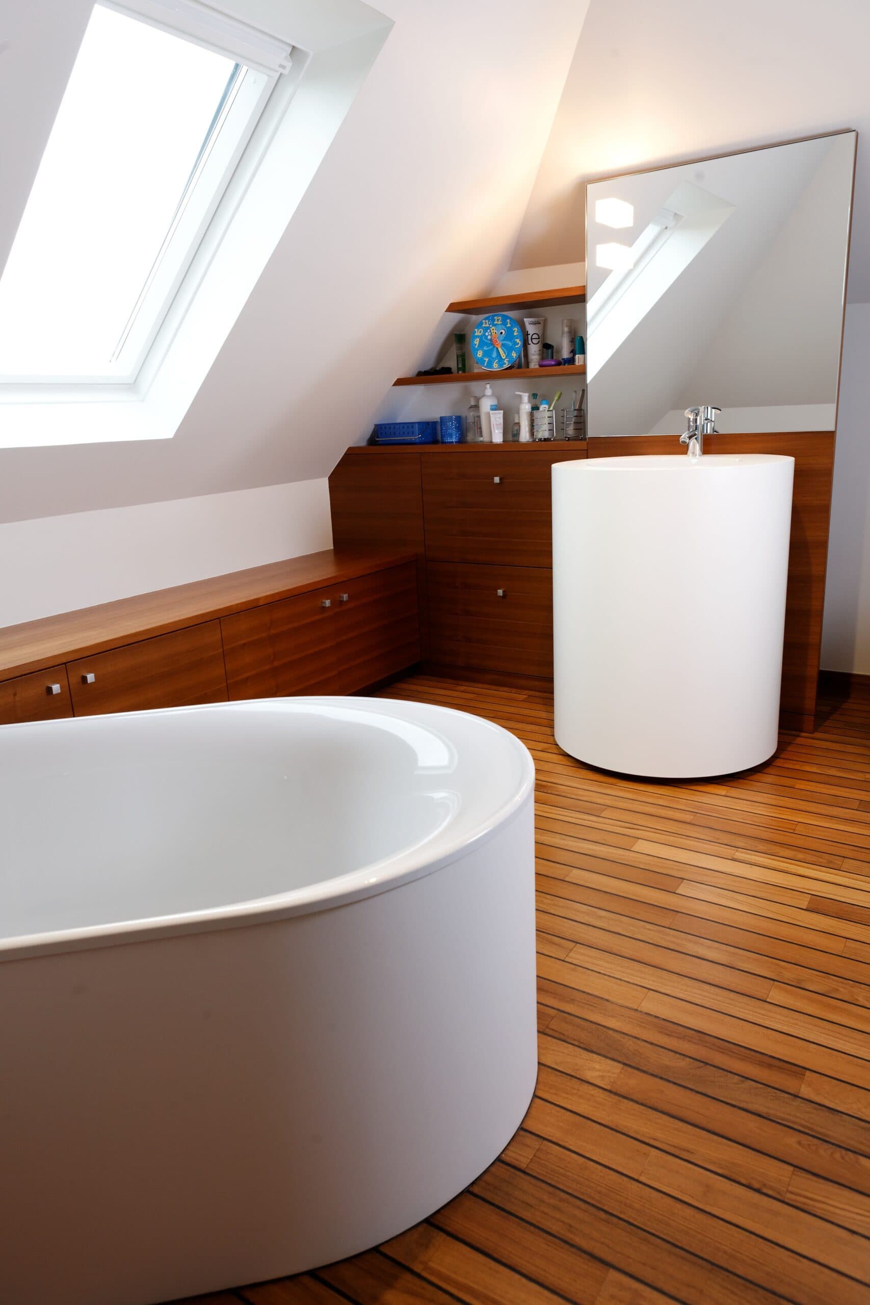 Salle de bain sous combles avec baignoire et parquet en teck