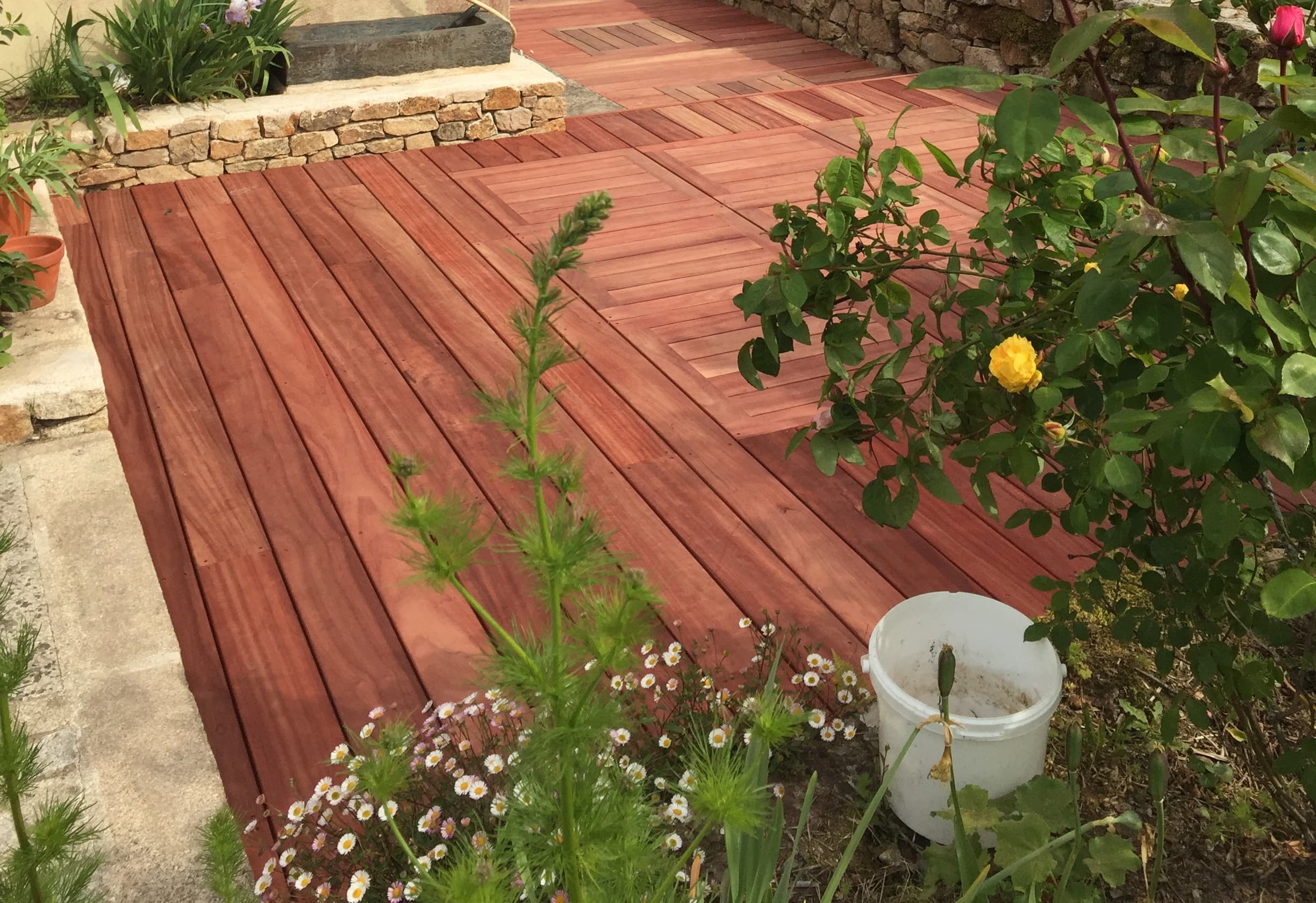 Terrasse en lames de bois exotique entourée de végétation