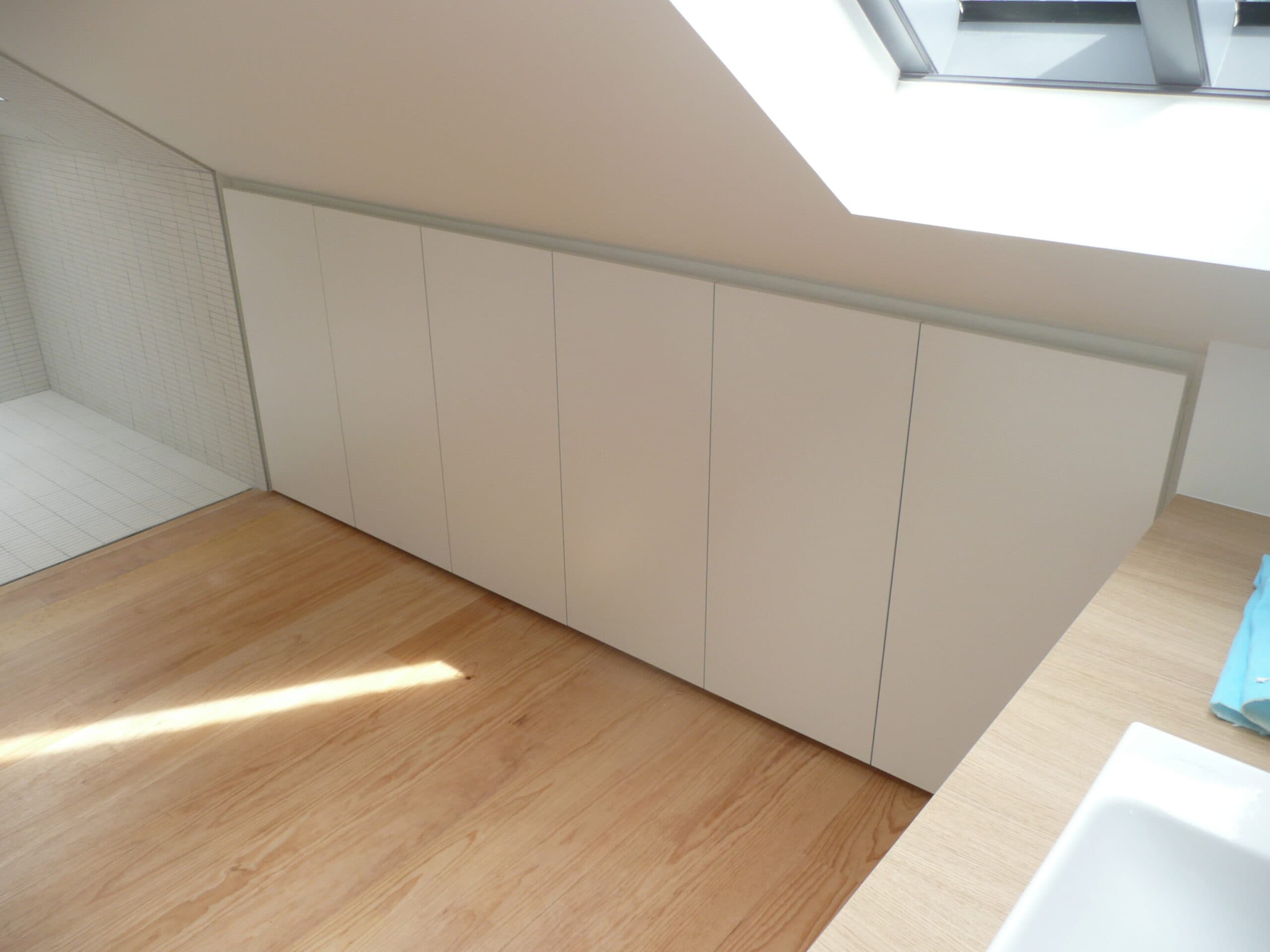 Placards blancs intégrés sous pente avec parquet clair