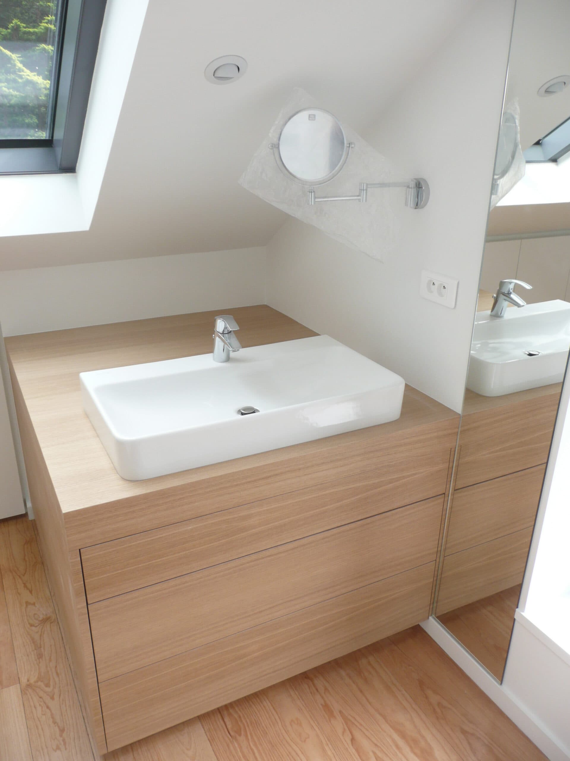 Meuble vasque en bois sous une fenêtre de toit