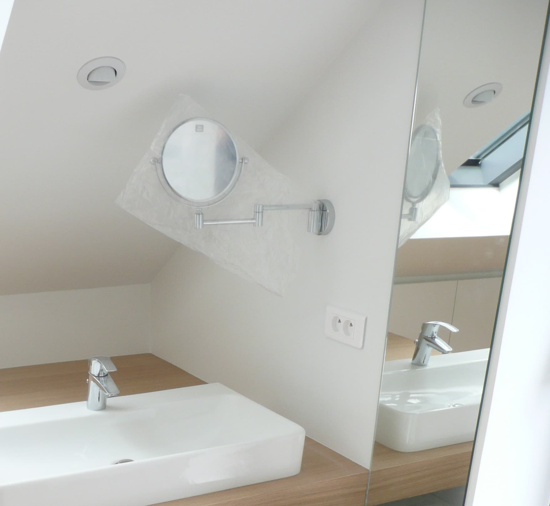 Vasque blanche et miroir grossissant dans une salle de bain