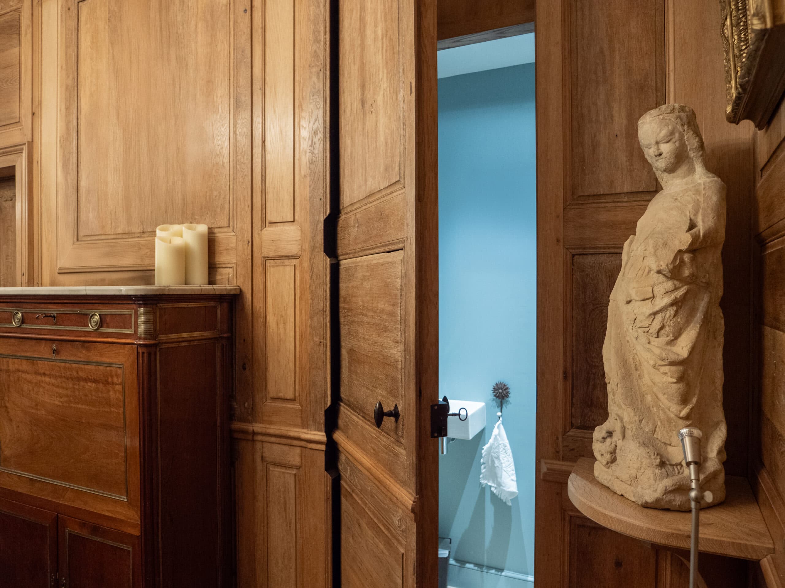 Porte en bois ancien ouvrant sur une salle de bain avec statue