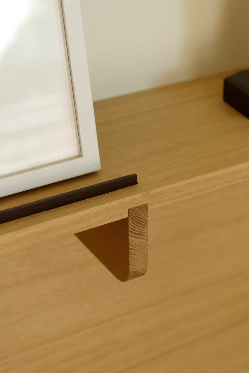 Détail d'une poignée en bois triangulaire sur un caisson en chêne