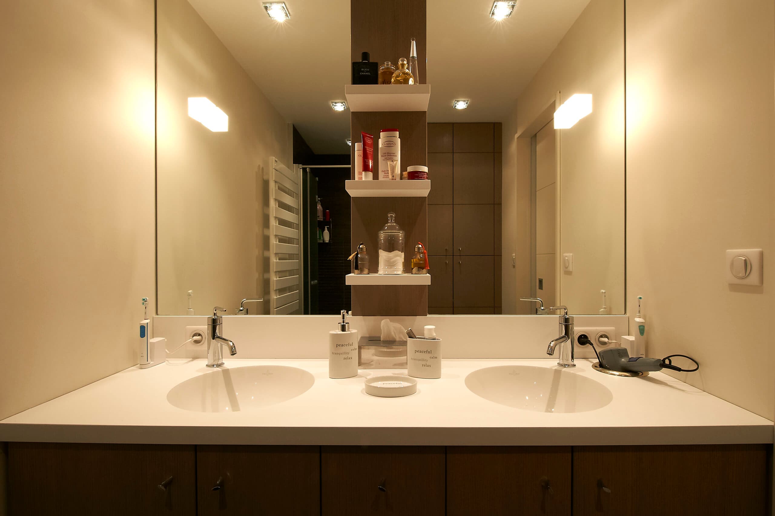 Double vasque blanche sous un grand miroir éclairé