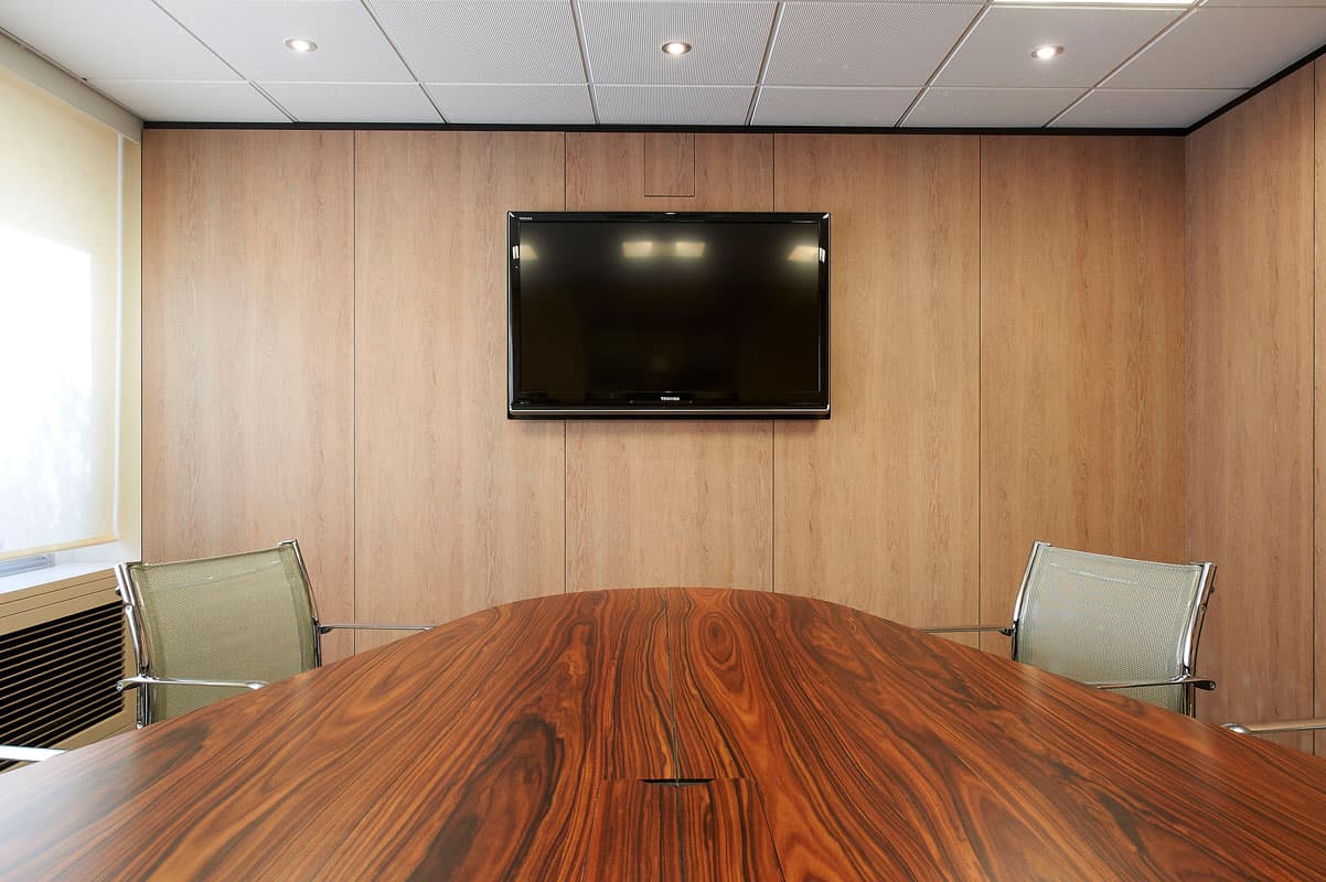 Salle de réunion habillée de bois avec écran mural et table en palissandre