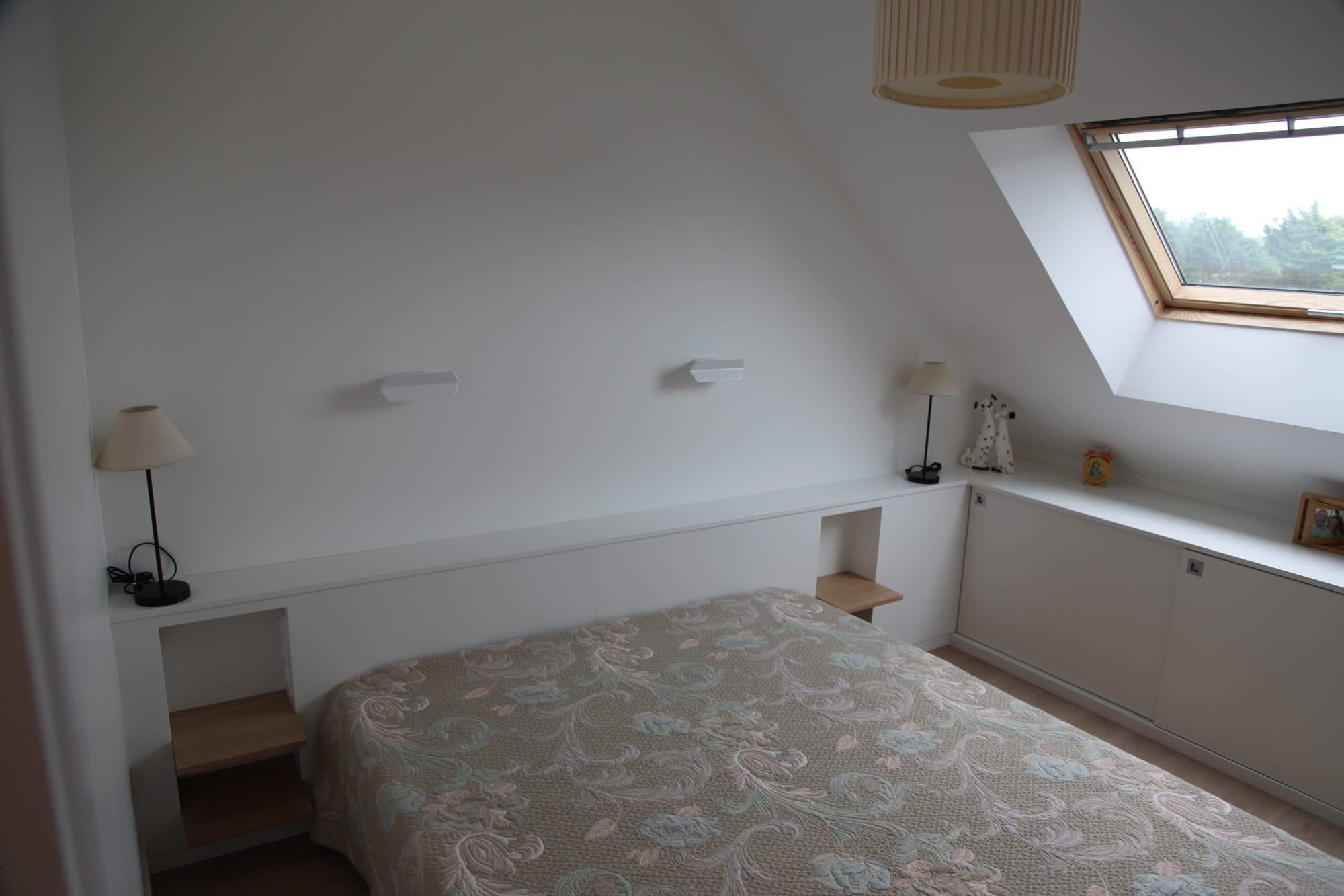 Chambre sous pente avec tête de lit et rangements blancs