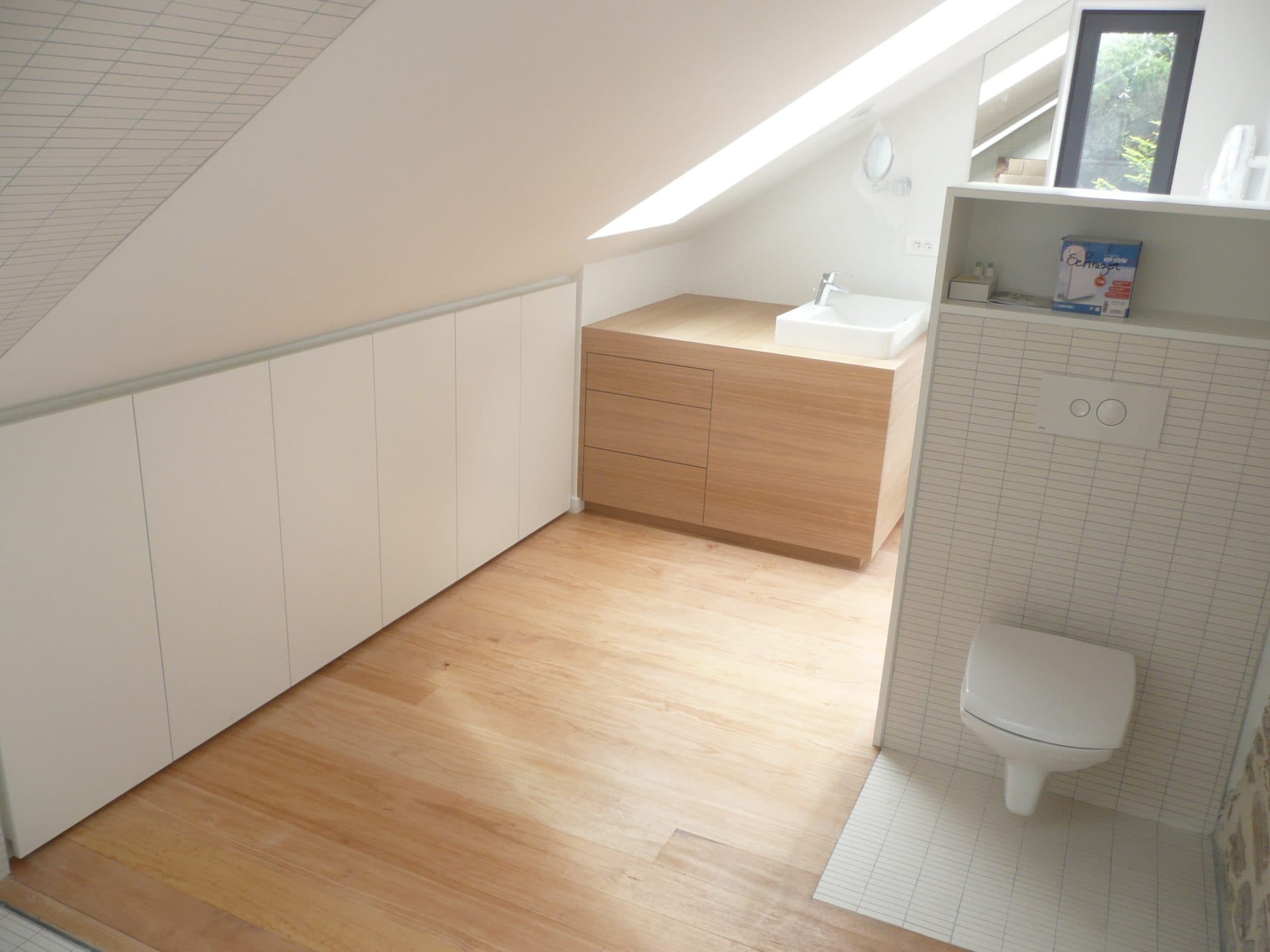 Salle de bain sous combles avec meuble vasque en bois et WC