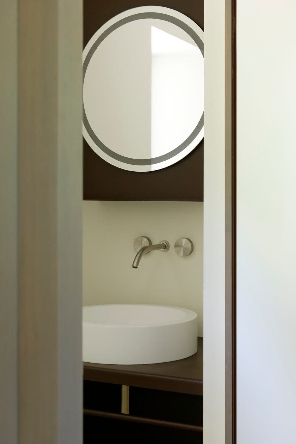 Salle de bain avec vasque ronde et miroir dans une niche bois