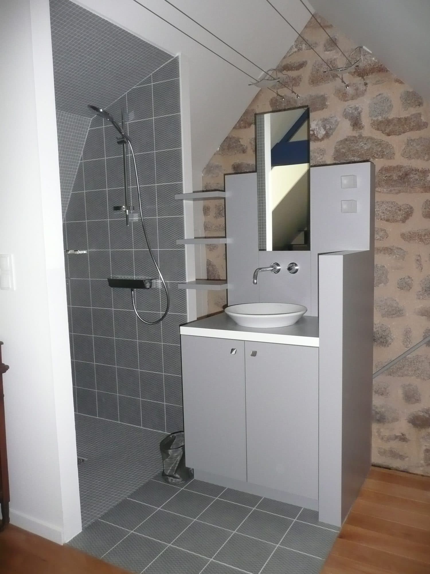 Douche et meuble vasque contre un mur en pierre