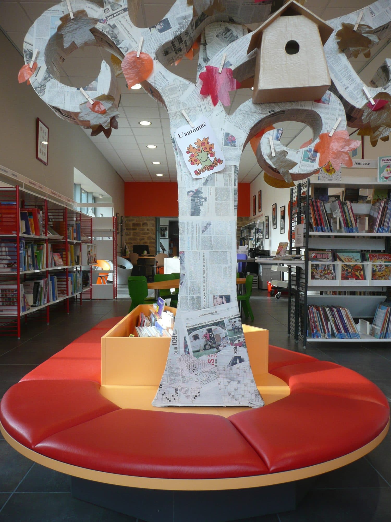 Espace jeunesse avec arbre décoratif et banquette rouge