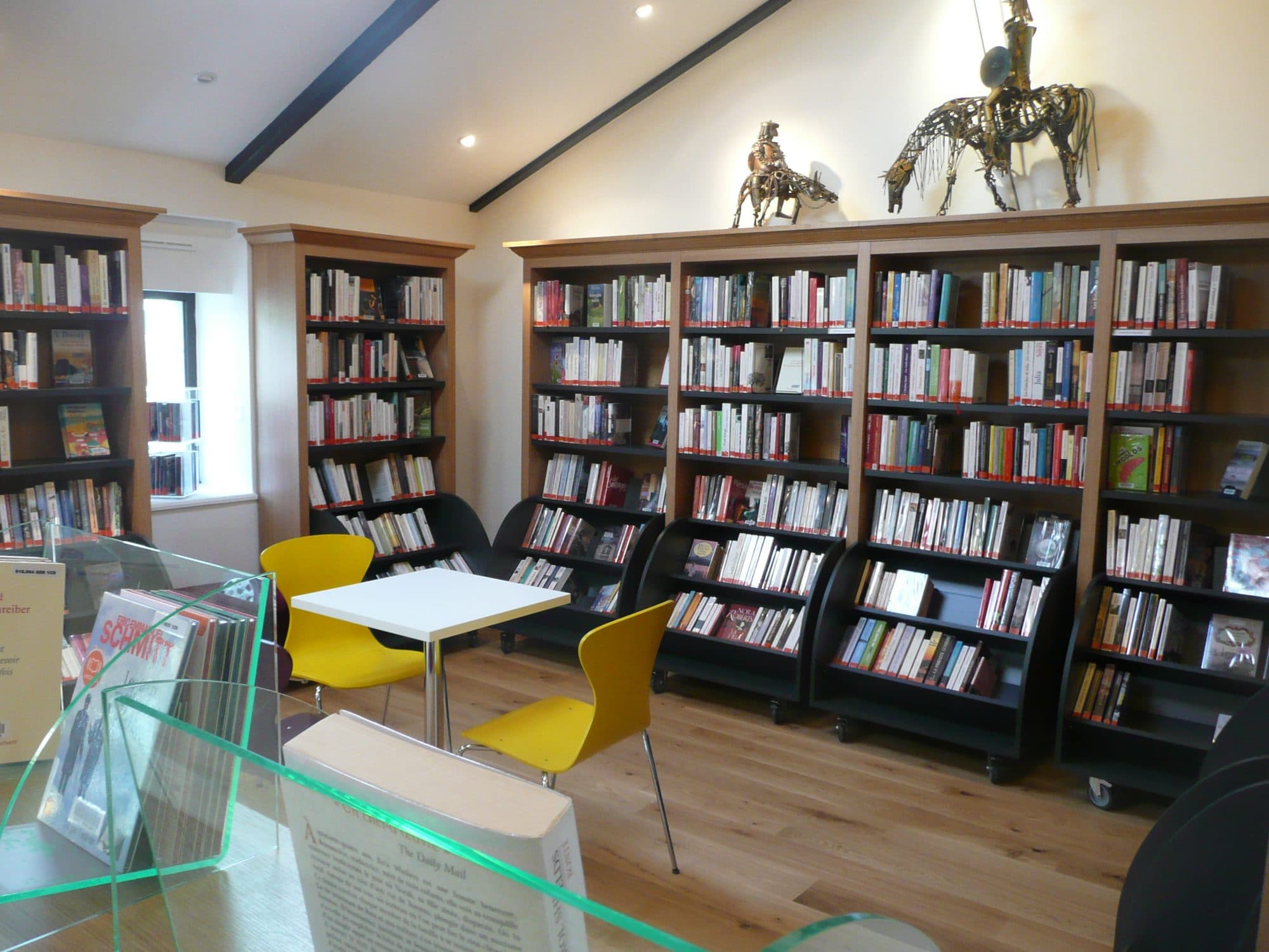 Salle de lecture avec rayonnages et tables jaunes