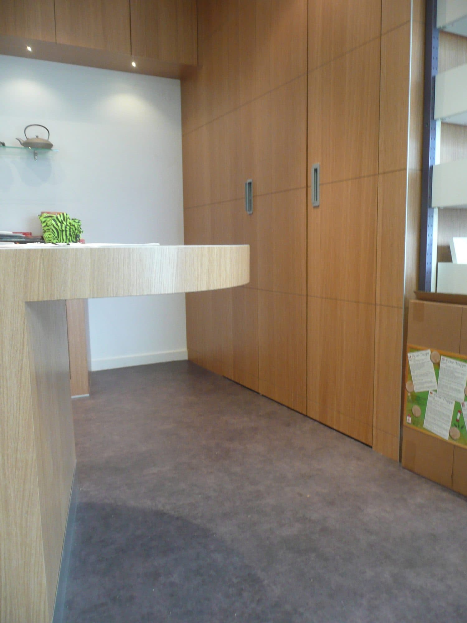 Banque d'accueil blanche et placards en bois