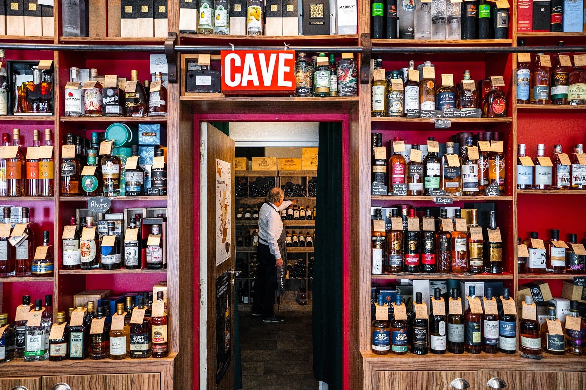 Mur de bouteilles rouge encadrant l'entrée d'une cave