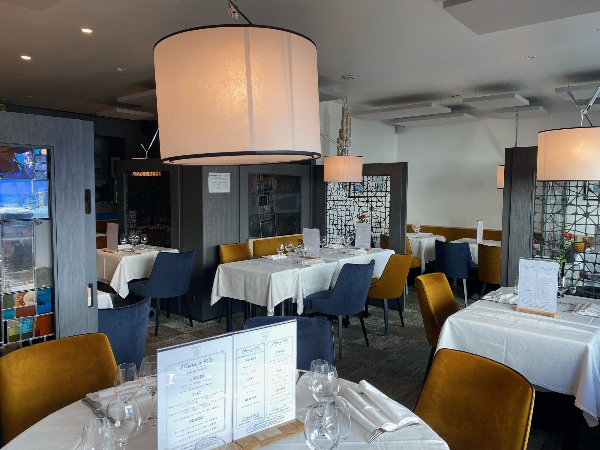 Salle de restaurant avec grande suspension et nappes blanches
