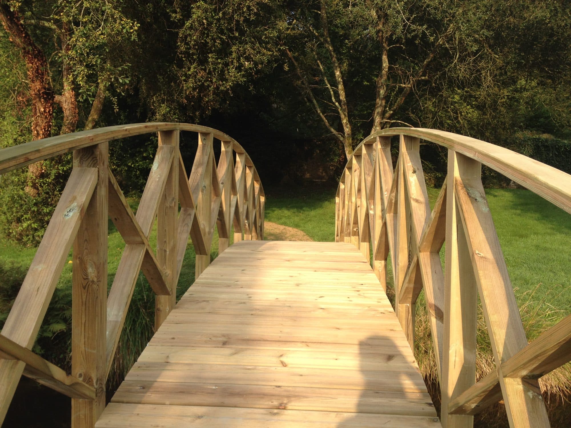 Passerelle en bois avec garde-corps croisés dans un jardin