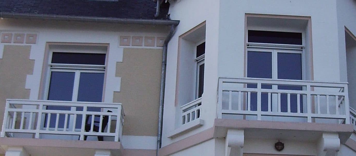 Balcons à garde-corps blancs sur une façade ancienne