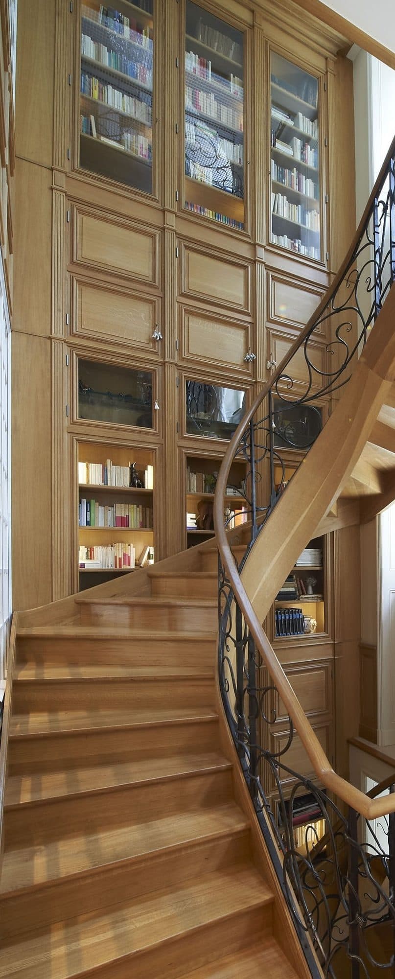 Escalier en bois avec rampe en fer forgé et bibliothèque