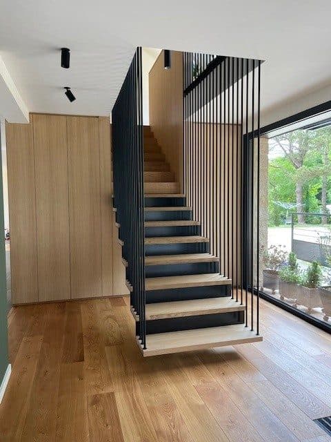Escalier suspendu en bois avec garde-corps à barreaux noirs