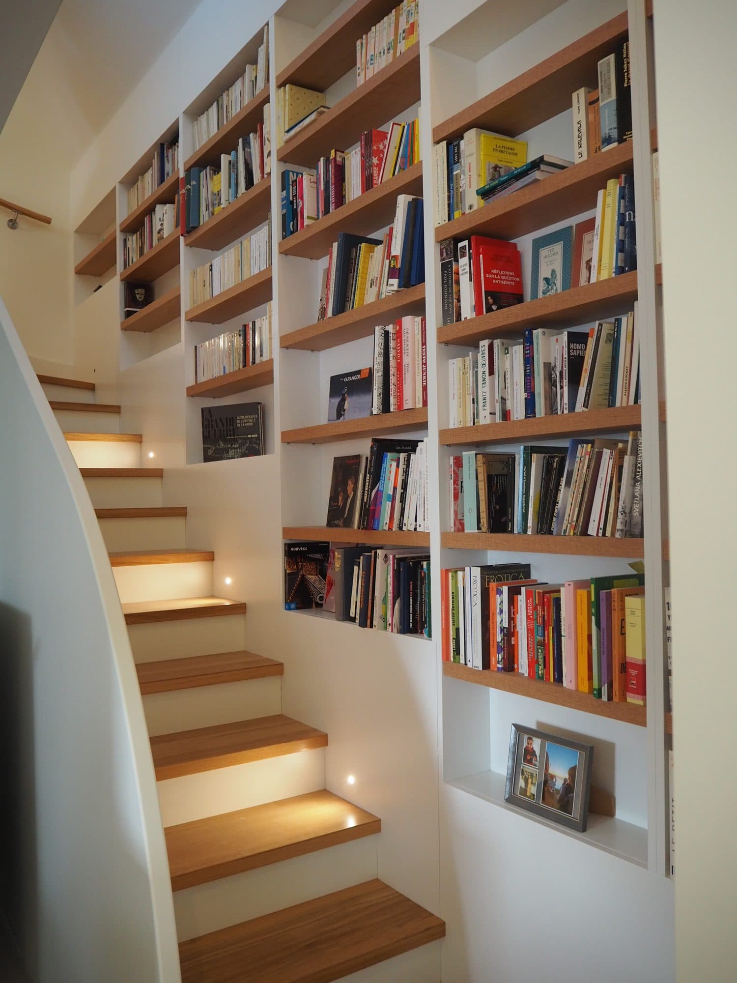 Escalier éclairé longé d'une bibliothèque encastrée