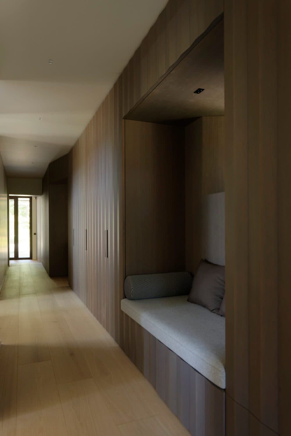 Couloir habillé de bois avec banquette dans une niche