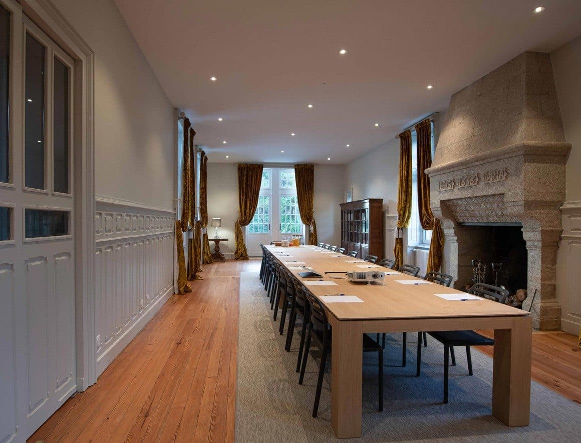 Longue table de réunion en chêne dans une salle à cheminée
