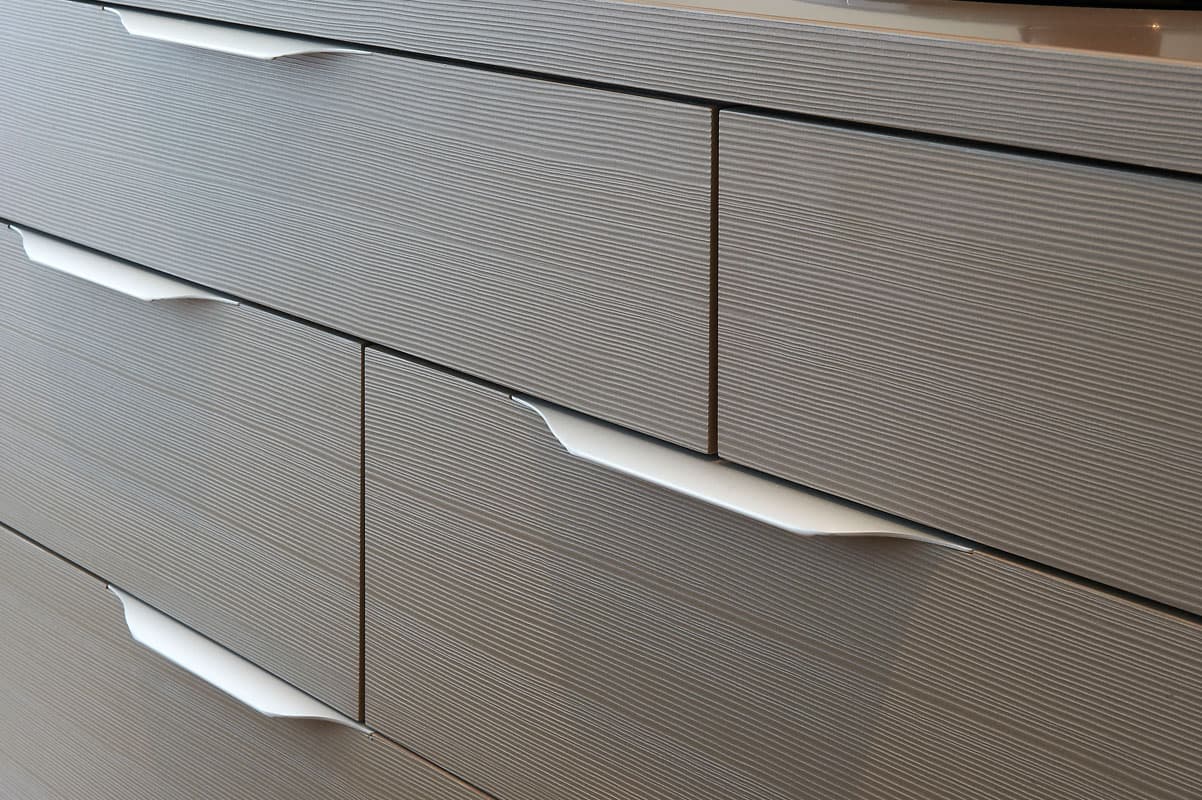Détail des poignées intégrées de tiroirs en bois gris strié